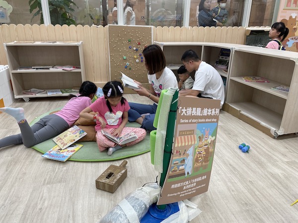 家長和小朋友在「閱．玩 樹蔭」閱讀與主題相關的圖書，興致一到更可即席配合場內設置及物資，以遊戲方式體驗故事情節。