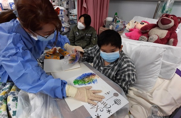 為強化可樂各種感官的協調能力，醫院遊戲師帶來顏料拓印以製作巨型聖誕卡；個性積極開朗的可樂慢慢適應後，竟然主動脫下手套，直接塗抹七色顏料，創造了色彩漸變的驚喜效果。