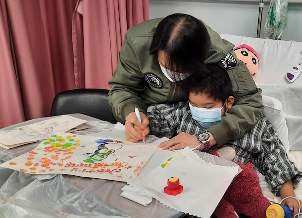 爸爸完全配合兒子，出手協助可樂在拓印聖誕卡上簽上大名。