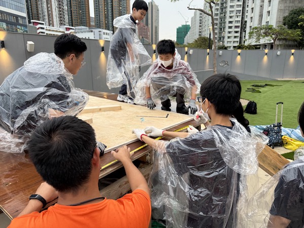 工作坊進行期間遇上雨點灑落,中學生們卻絲毫不受影響,依舊興致勃勃,披上雨衣、專心致志地建造大型滑梯。