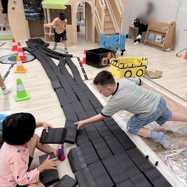 小朋友分工合作，有人鋪設新路、有人維修被車壓壞的路、有人負責補給材料，特長特大馬路已經接近完成！